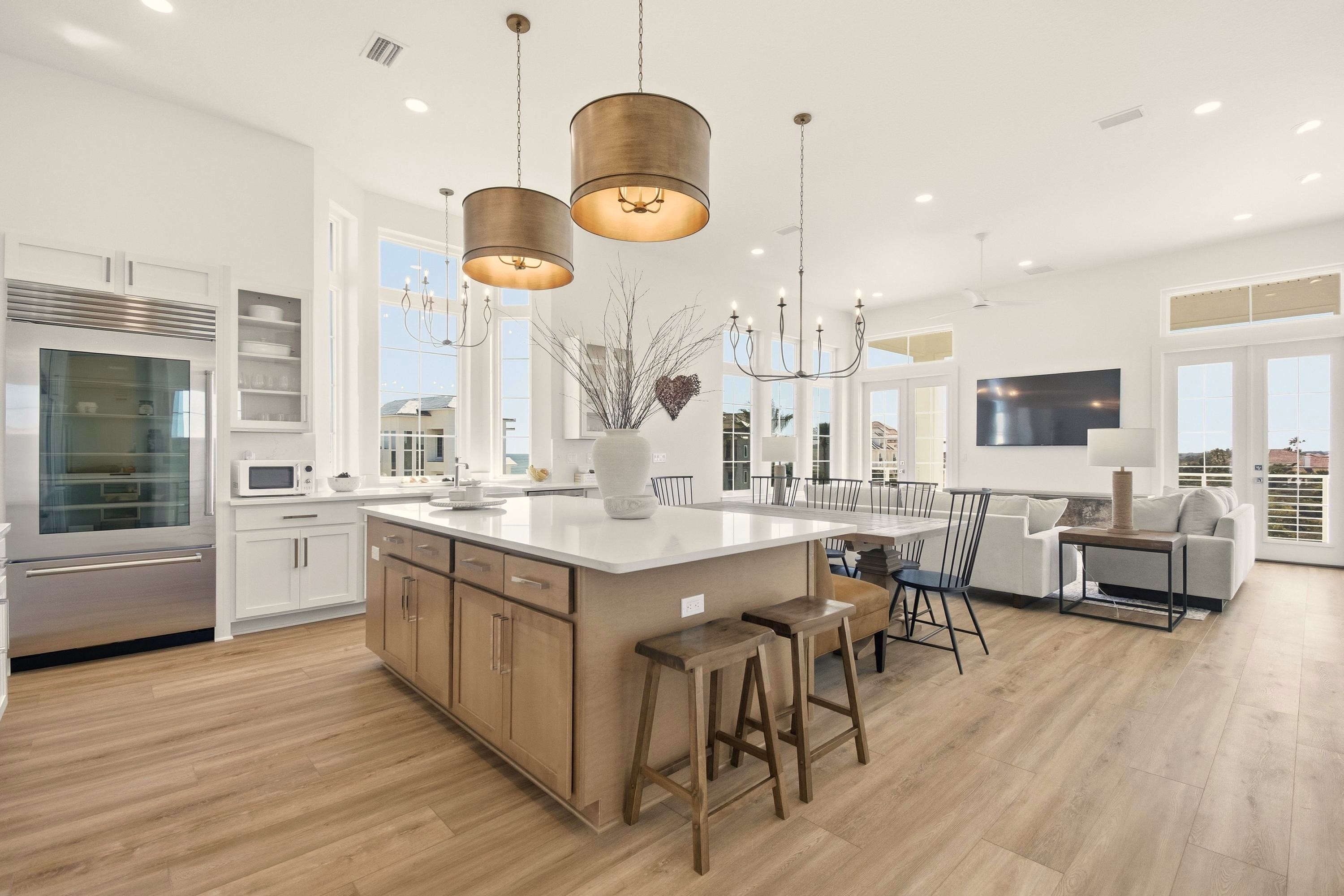 Beach days start here: everyone gathers at the big island to pack snacks, then comes back to this bright open space for showers, dinner, and a movie while the kids pass out on the couch—simple, easy, together.
