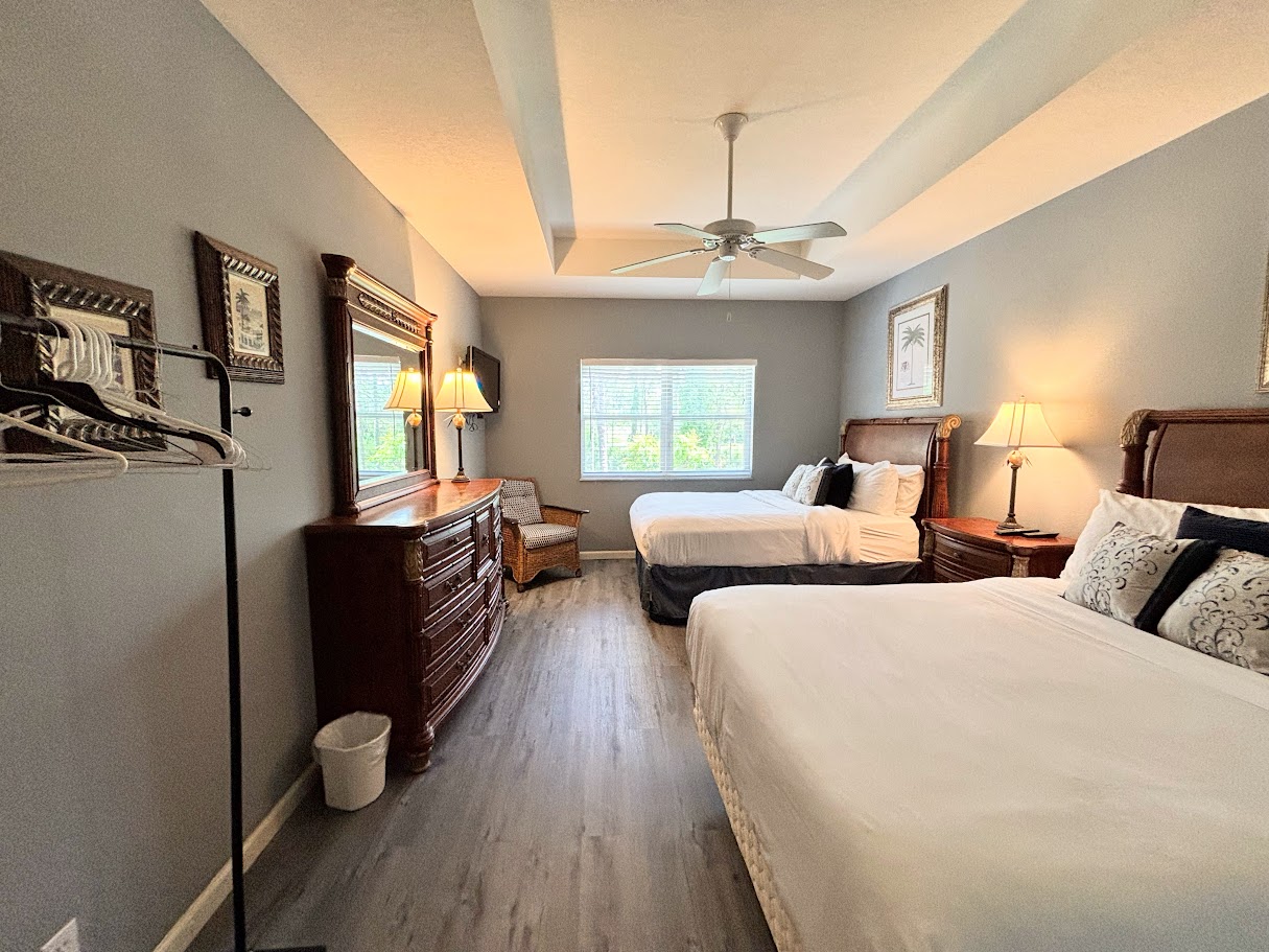 Spacious bedroom with two beds, wood-look flooring, dresser storage, and a relaxing setup.