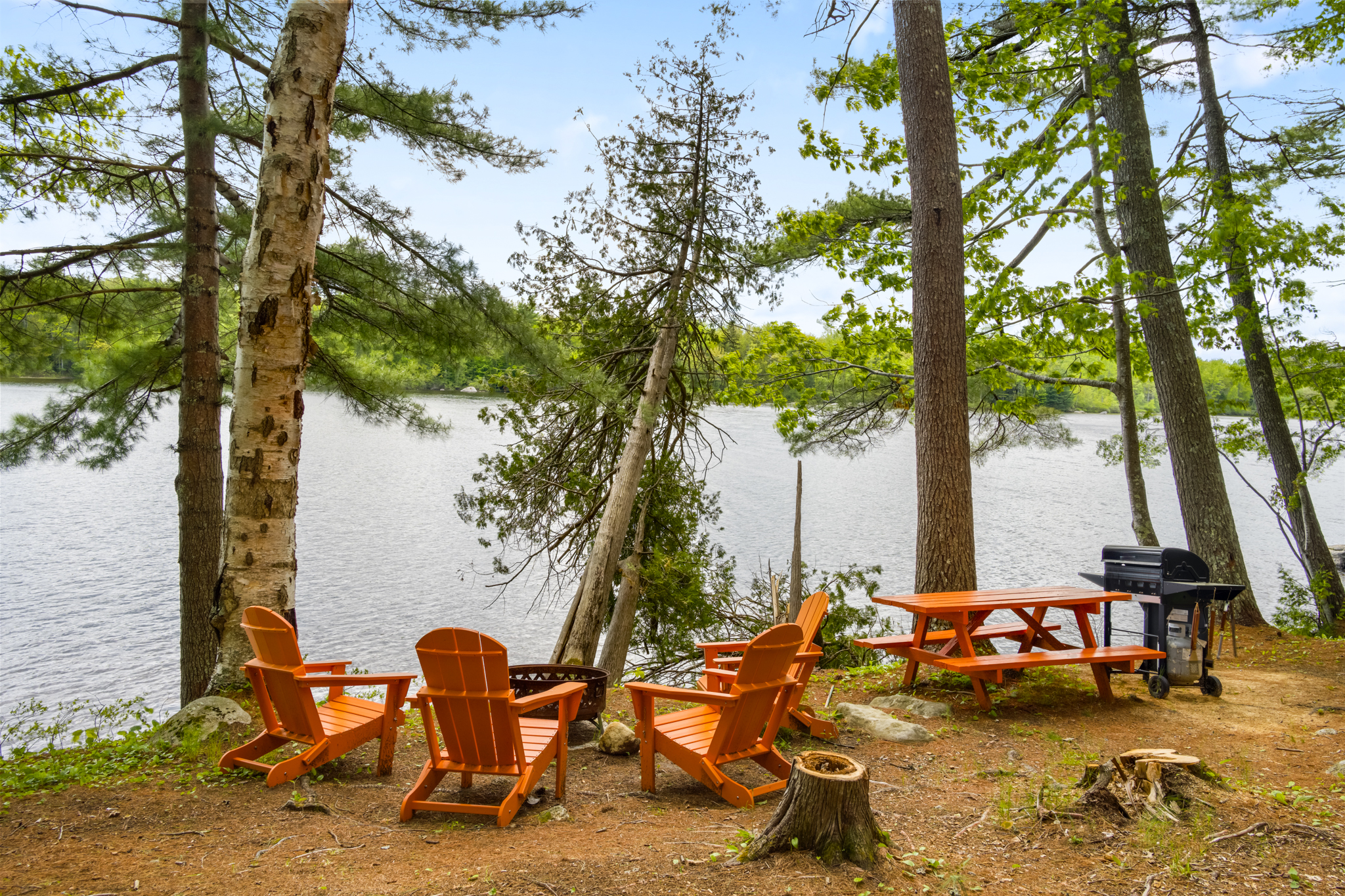 Cozy outdoor dining with wooden chairs and log firepit with laview