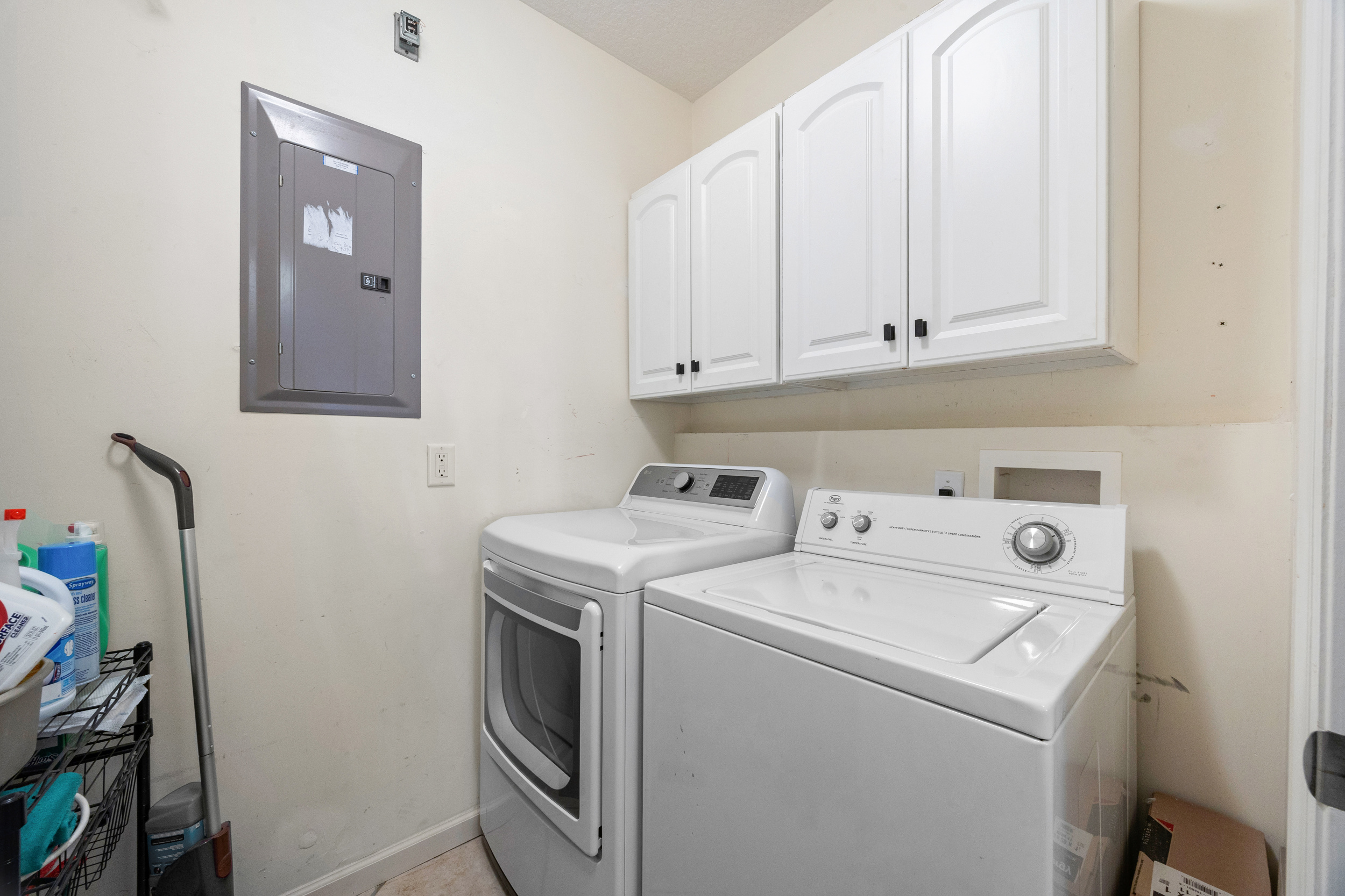Convenient laundry room with full‑size washer and dryer, storage cabinets, and cleaning essentials.