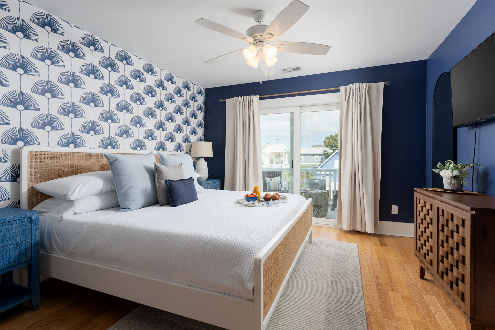 Bright third-floor king bedroom with coastal design, natural light, and access to a private balcony.