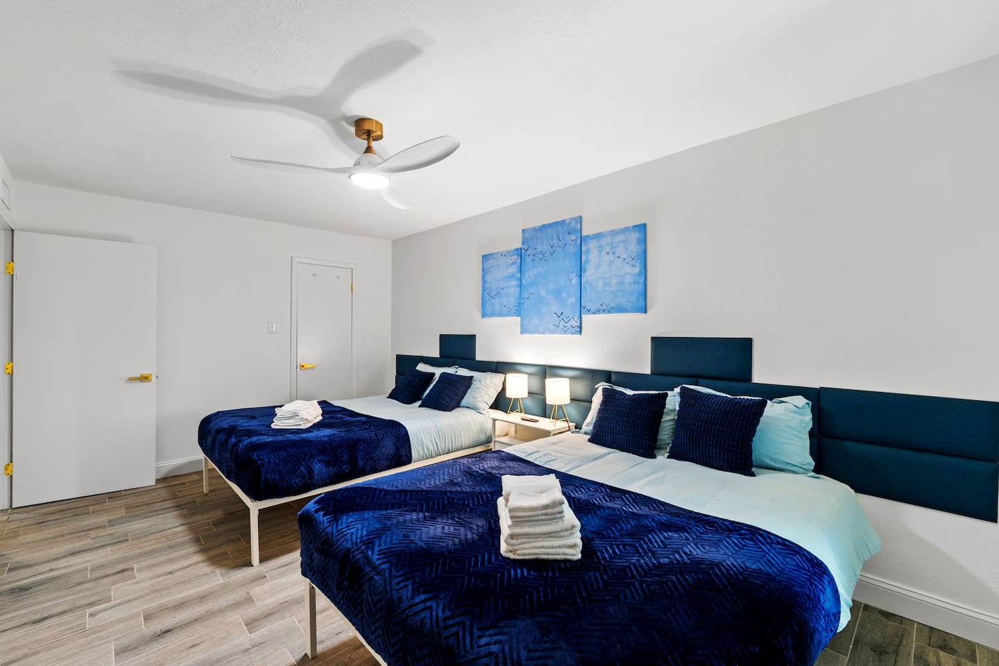 Spacious bedroom with two plush queen beds, blackout curtains, and a smart TV—ideal for families or groups to unwind in comfort.