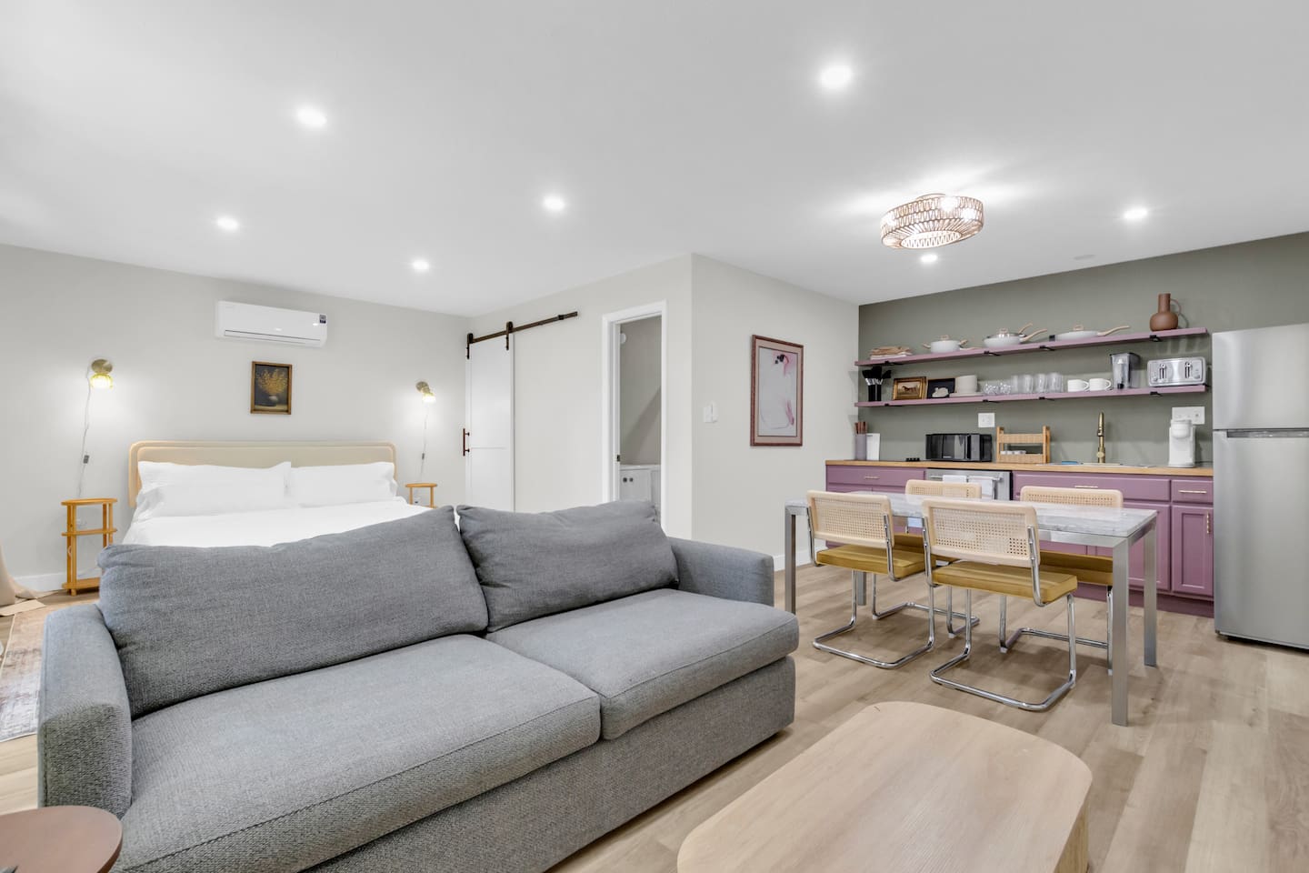 Open-concept 500 sq ft studio featuring a king bed, full kitchen, spacious couch, and TV—perfect blend of comfort and style in Dallas.