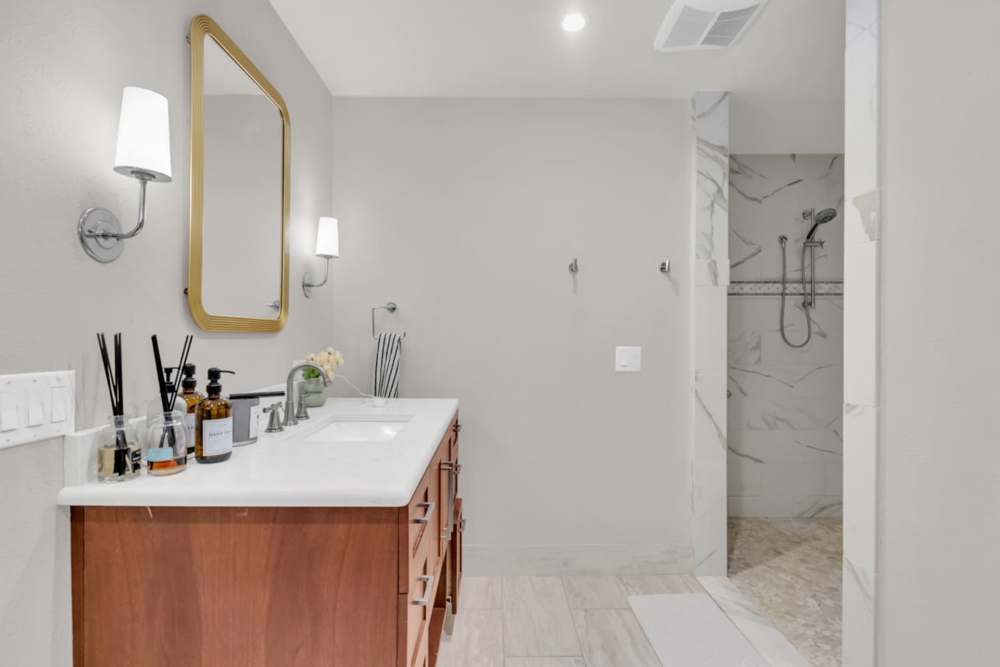 Oversized primary bathroom featuring a spacious single vanity and stocked with essential bath and body products for a comfortable, hotel-style experience.