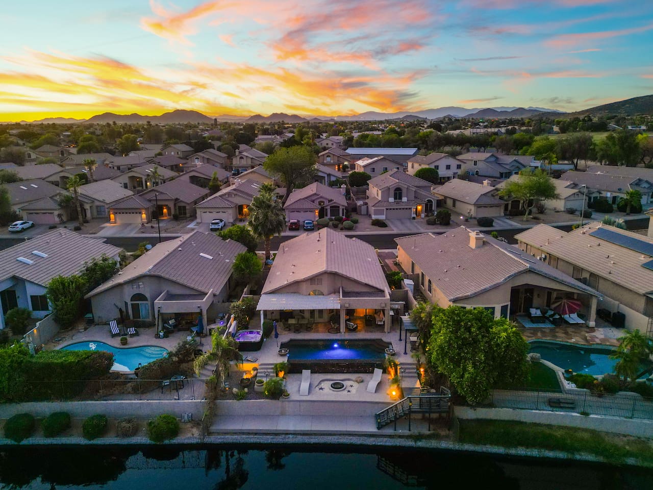 An aerial view that puts it all in perspective — your home sits right on the lake, with a glowing pool out back and the mountains painted in the sunset sky. Pure Arizona magic.