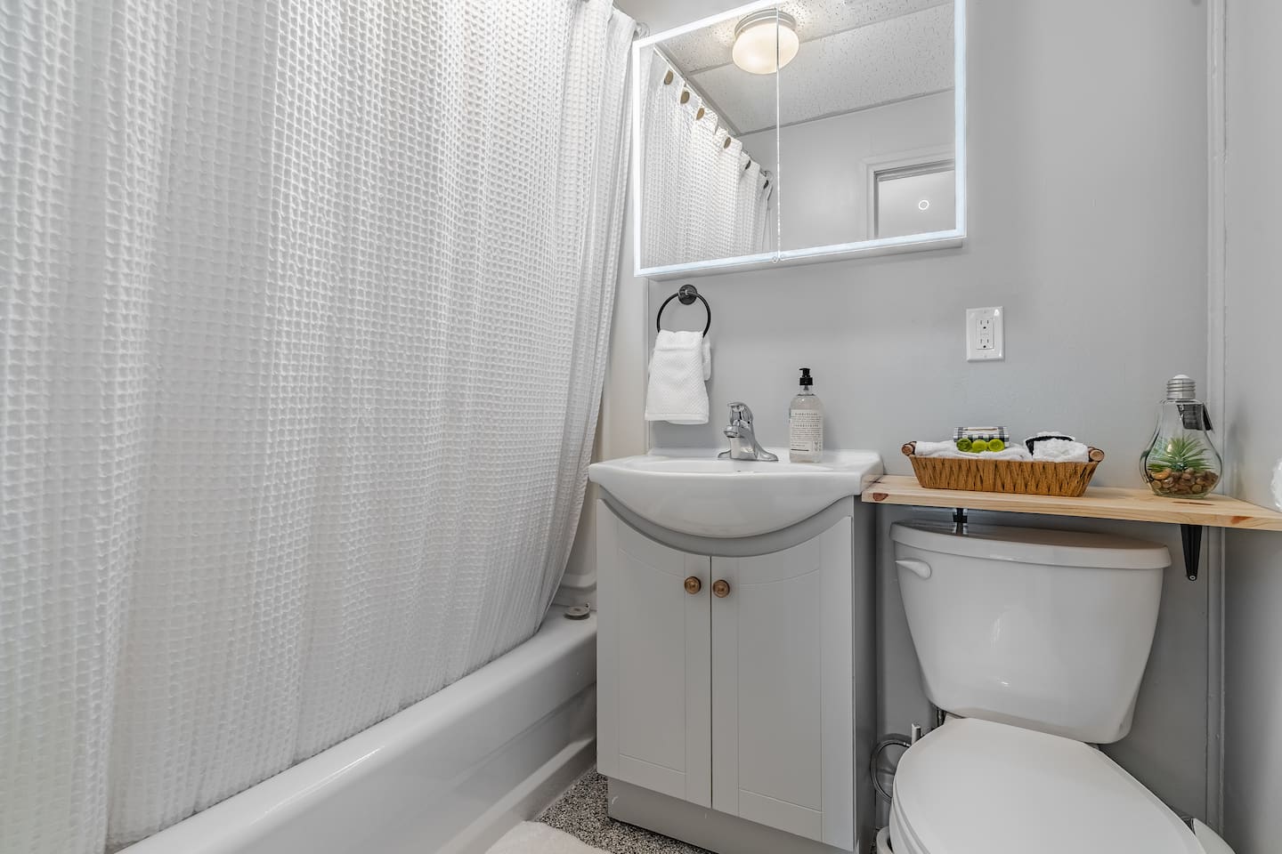 Basement full bathroom with tub/shower and lighted mirror.