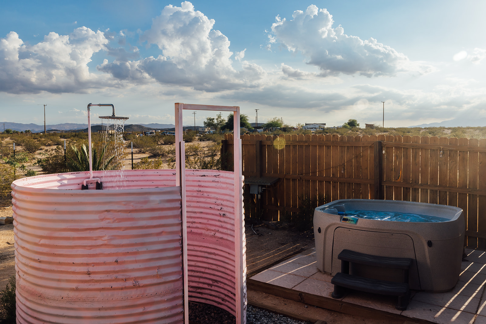 Private outdoor pink shower and hot tub set against expansive desert skies — perfect for relaxation under the sun or stars.