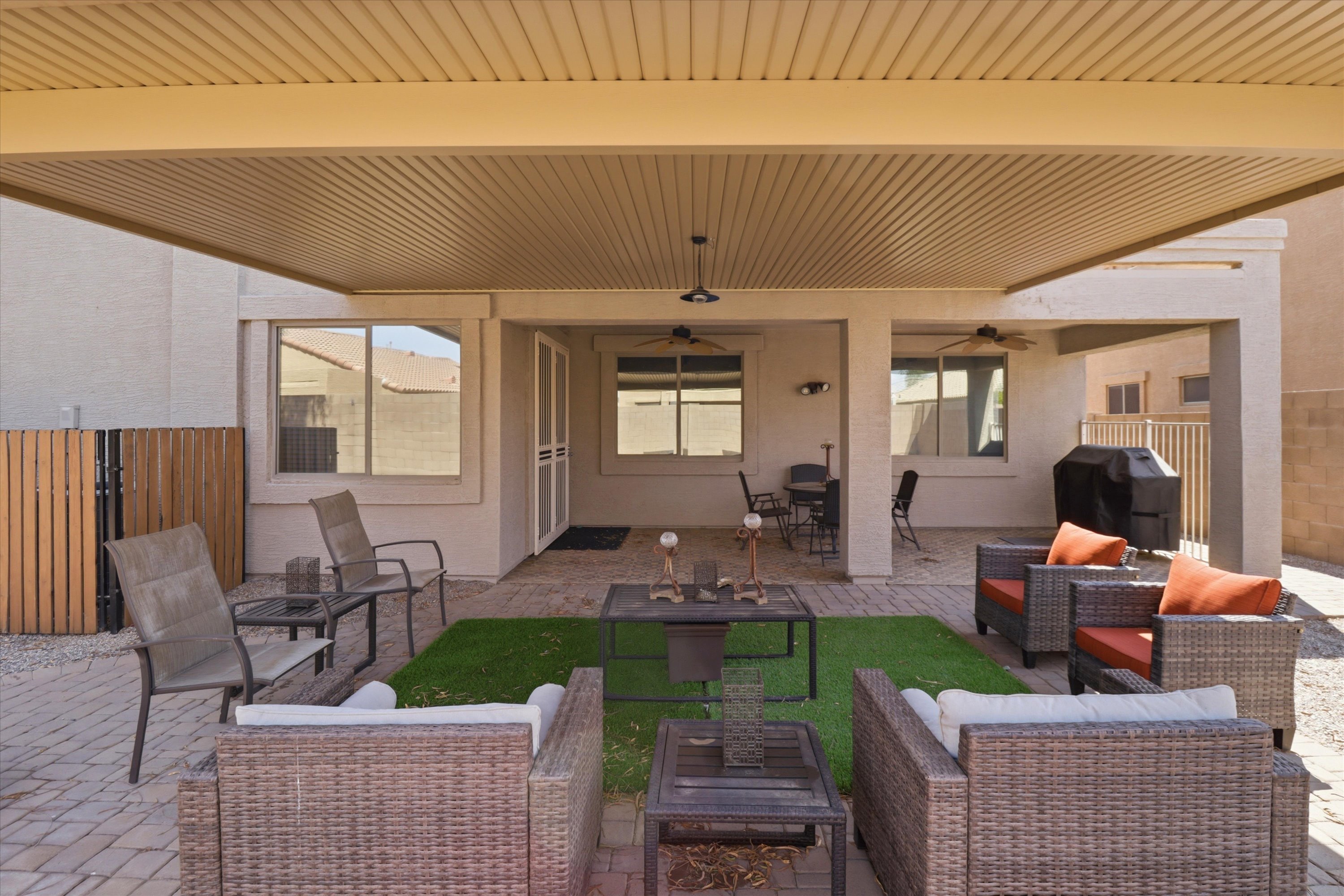 Covered backyard patio with lounge seating, BBQ grill, and space to hang out outside.