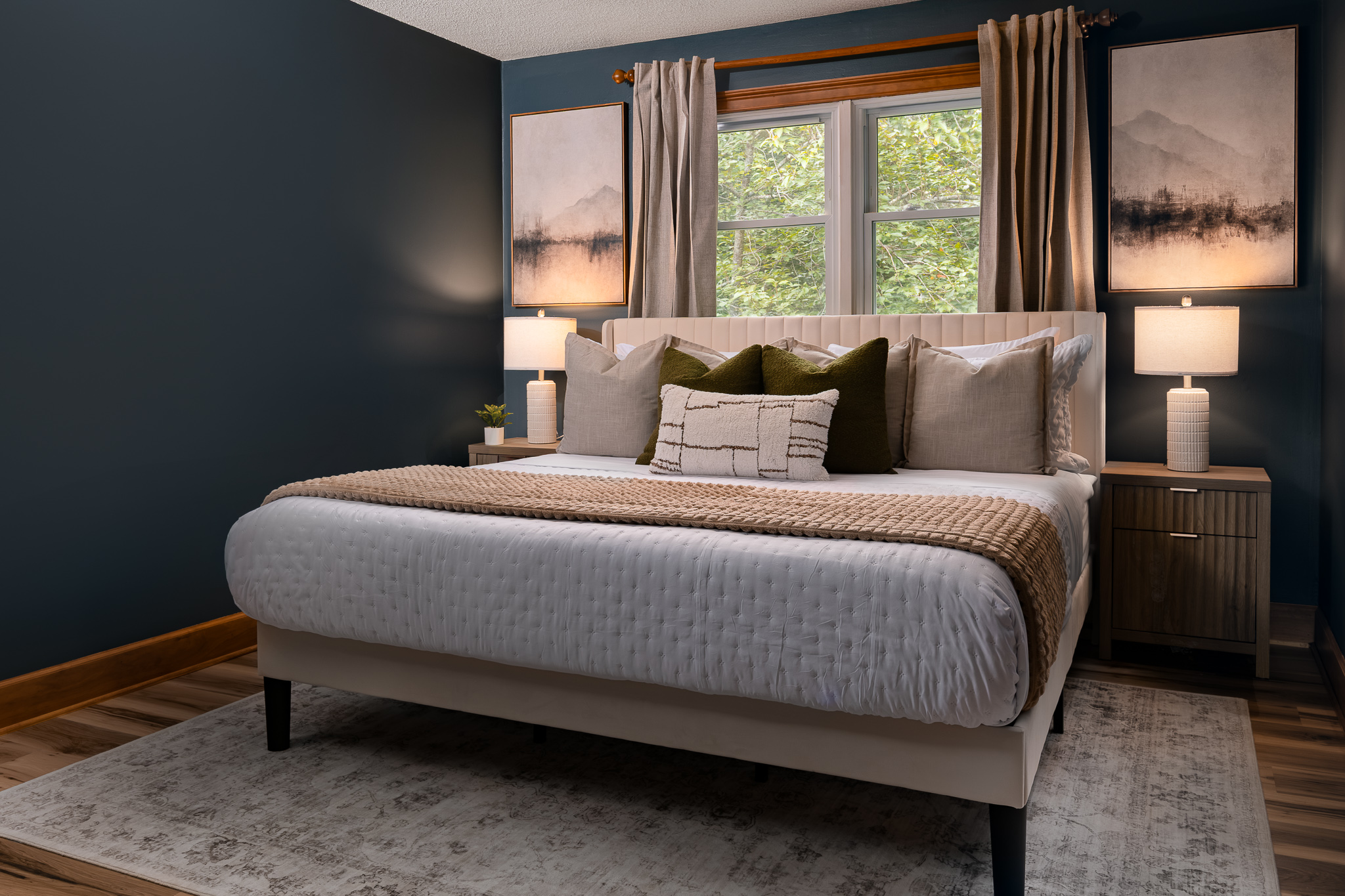 {Bedroom 3} Settle into this serene king bedroom with deep blue walls, layered bedding, and peaceful forest views.