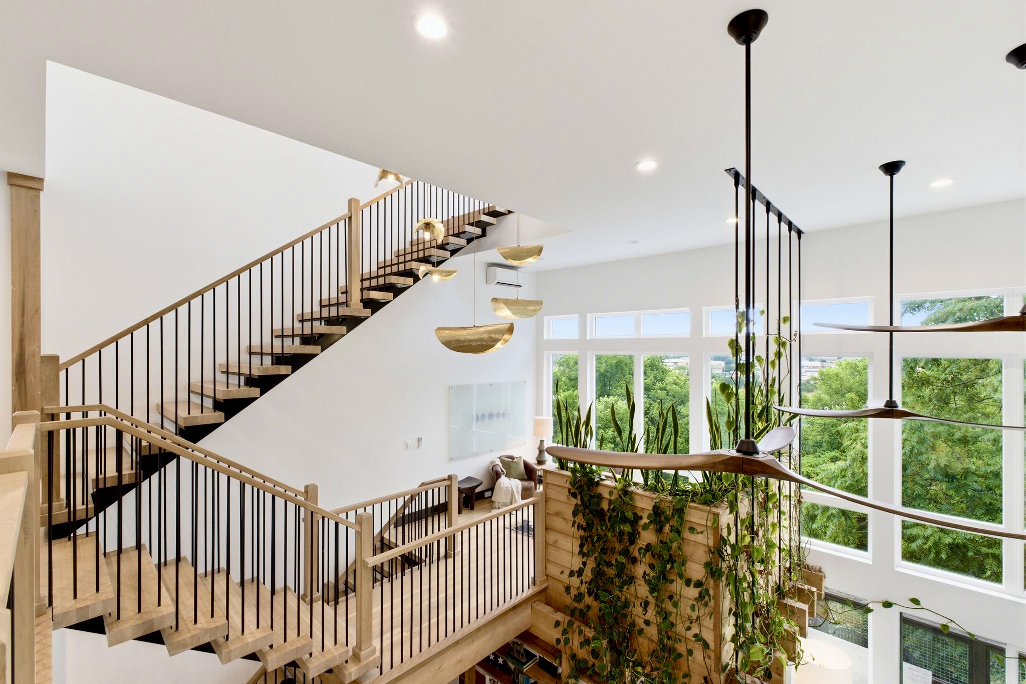 Sun-drenched stairwell w/ trailing plants, wood steps & walls of glass bringing the outside in.

