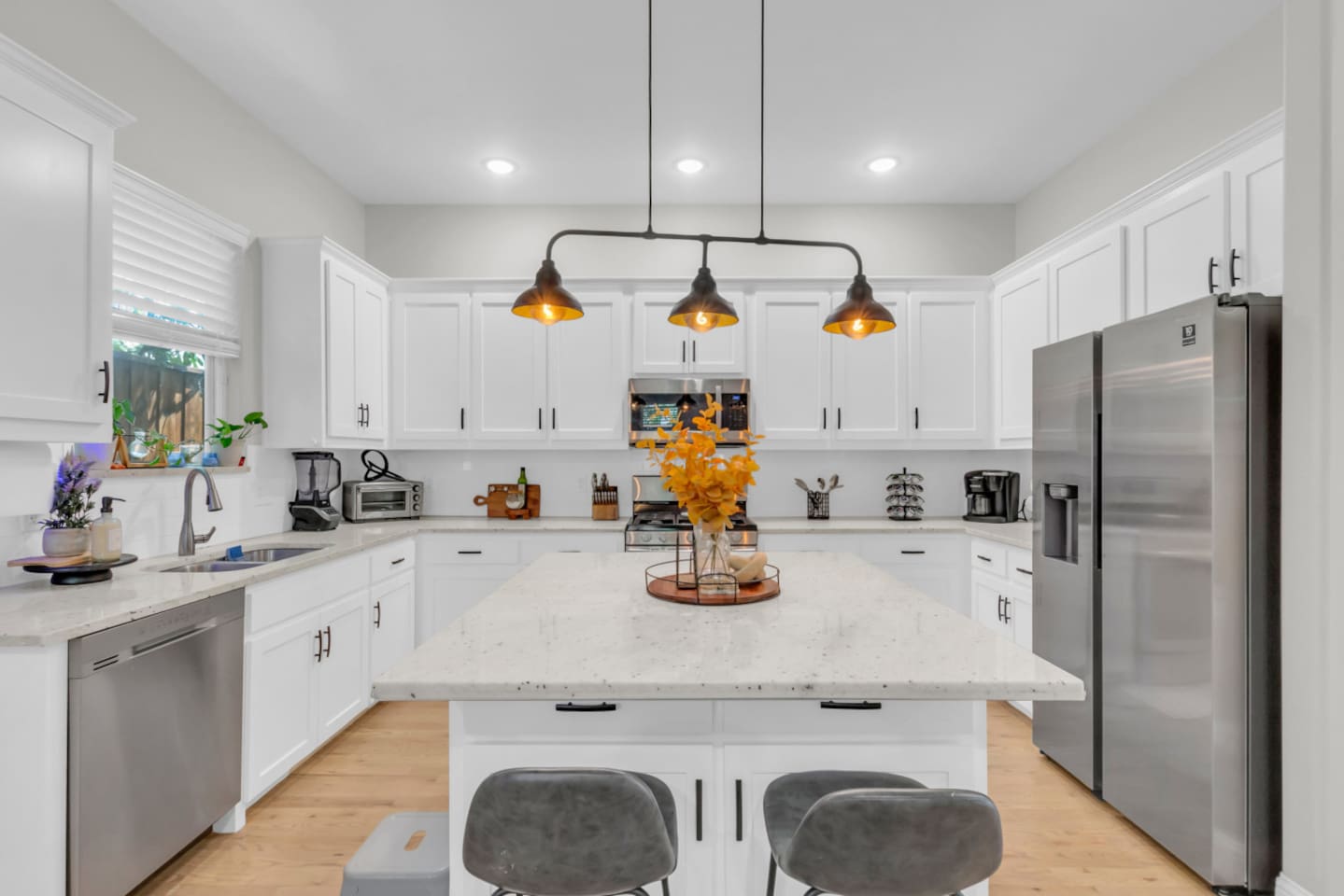 Open kitchen with pendant lighting and stainless steel appliances.