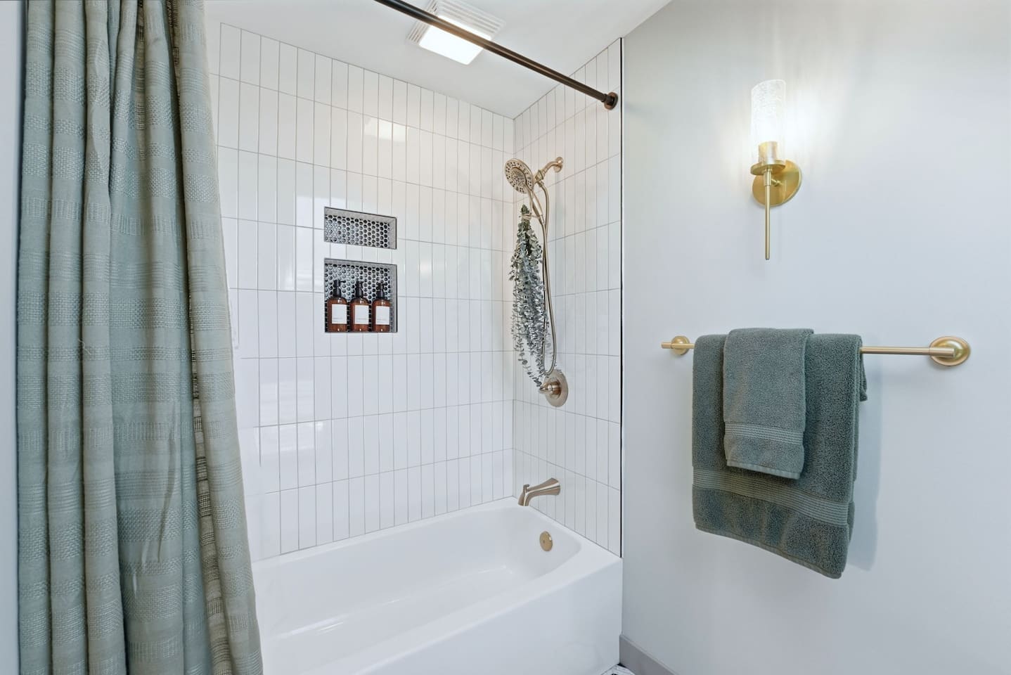 Clean and modern shower-tub combo with sleek tilework and stylish gold accents for a fresh, inviting feel 
