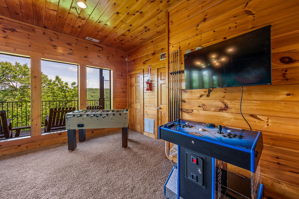 Game room with large windows offering a scenic mountain views and access to a balcony with rocking chairs