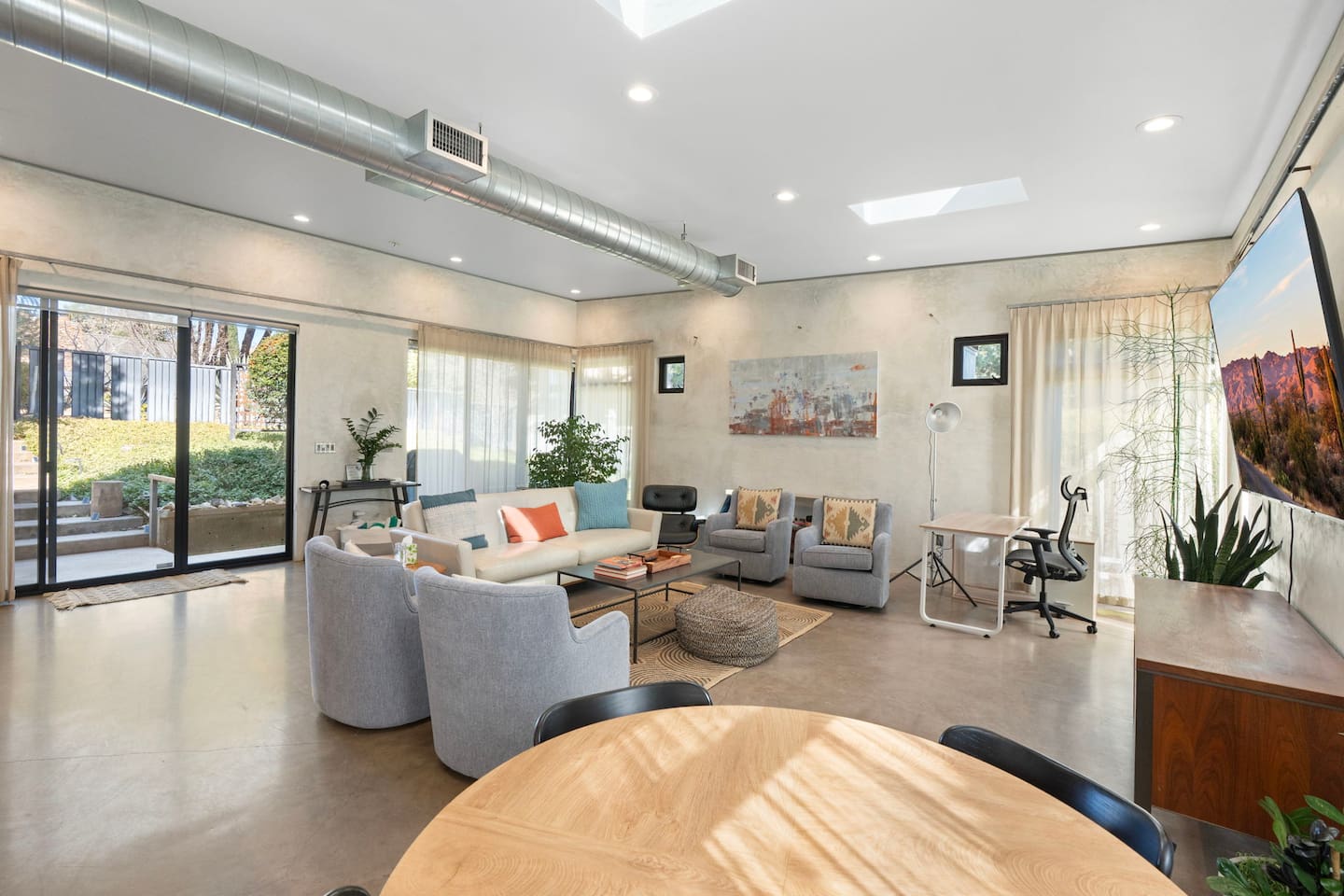 Bright open living space with comfortable seating, workspace area, and seamless indoor-outdoor access.