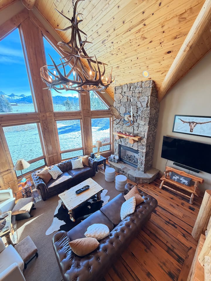 This main-level living room boasts massive floor-to-ceiling windows with stunning mountain views!