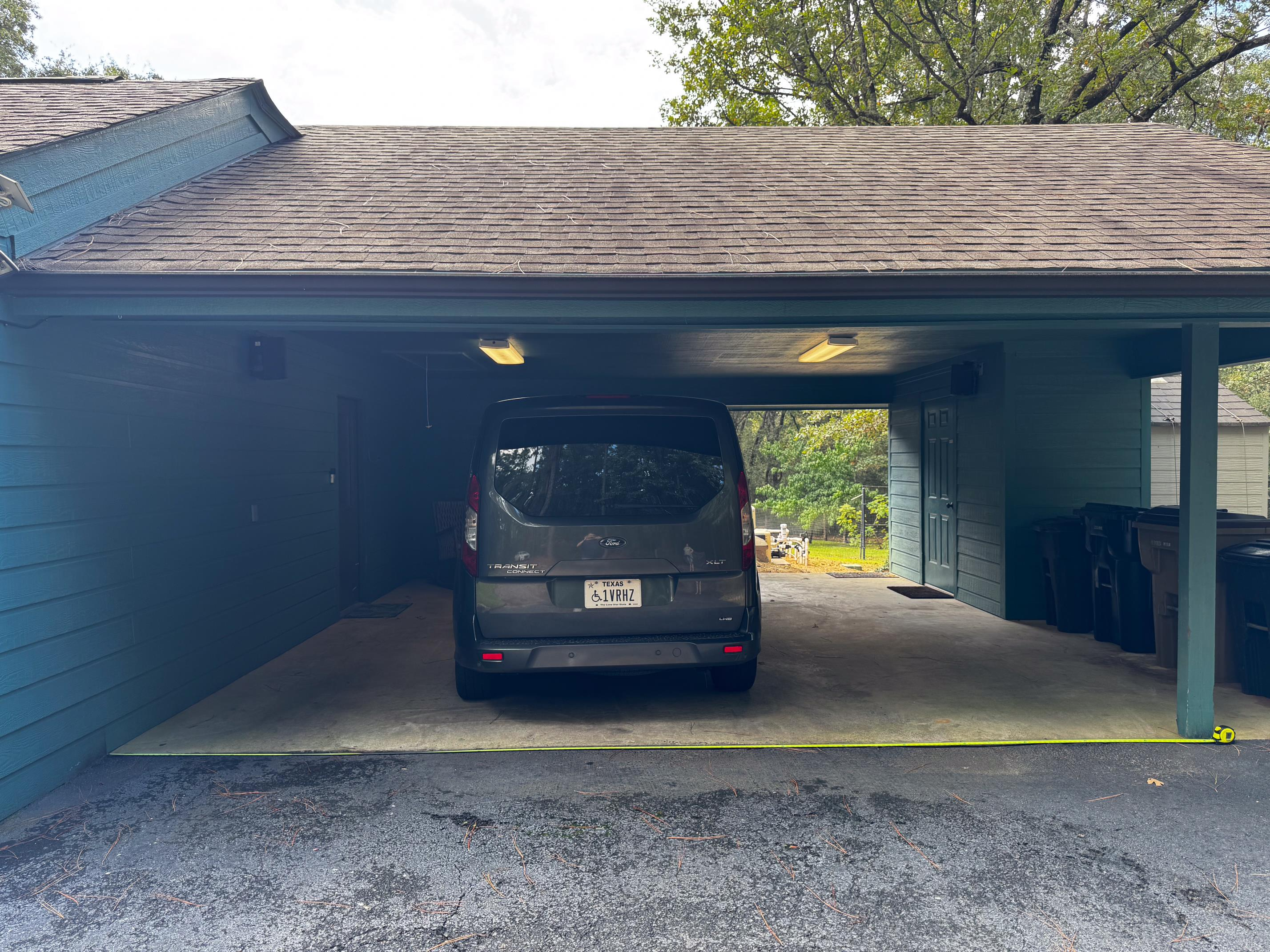 View into the carport where the garbage cans are.