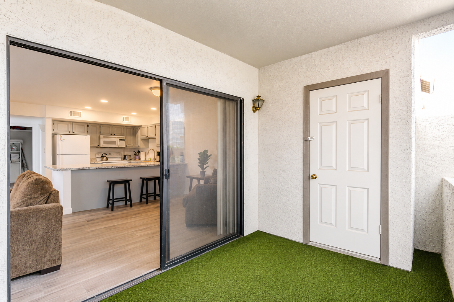 Private covered patio with turf flooring, storage closet, and sliding door access back into the living room and kitchen.
