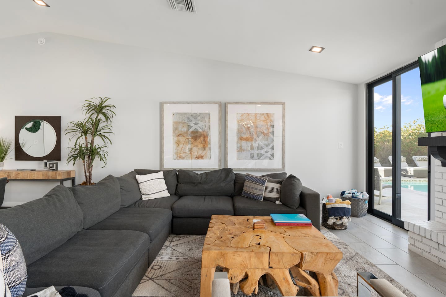 Spacious living room featuring large, cozy couches with a stunning view of the poolside.