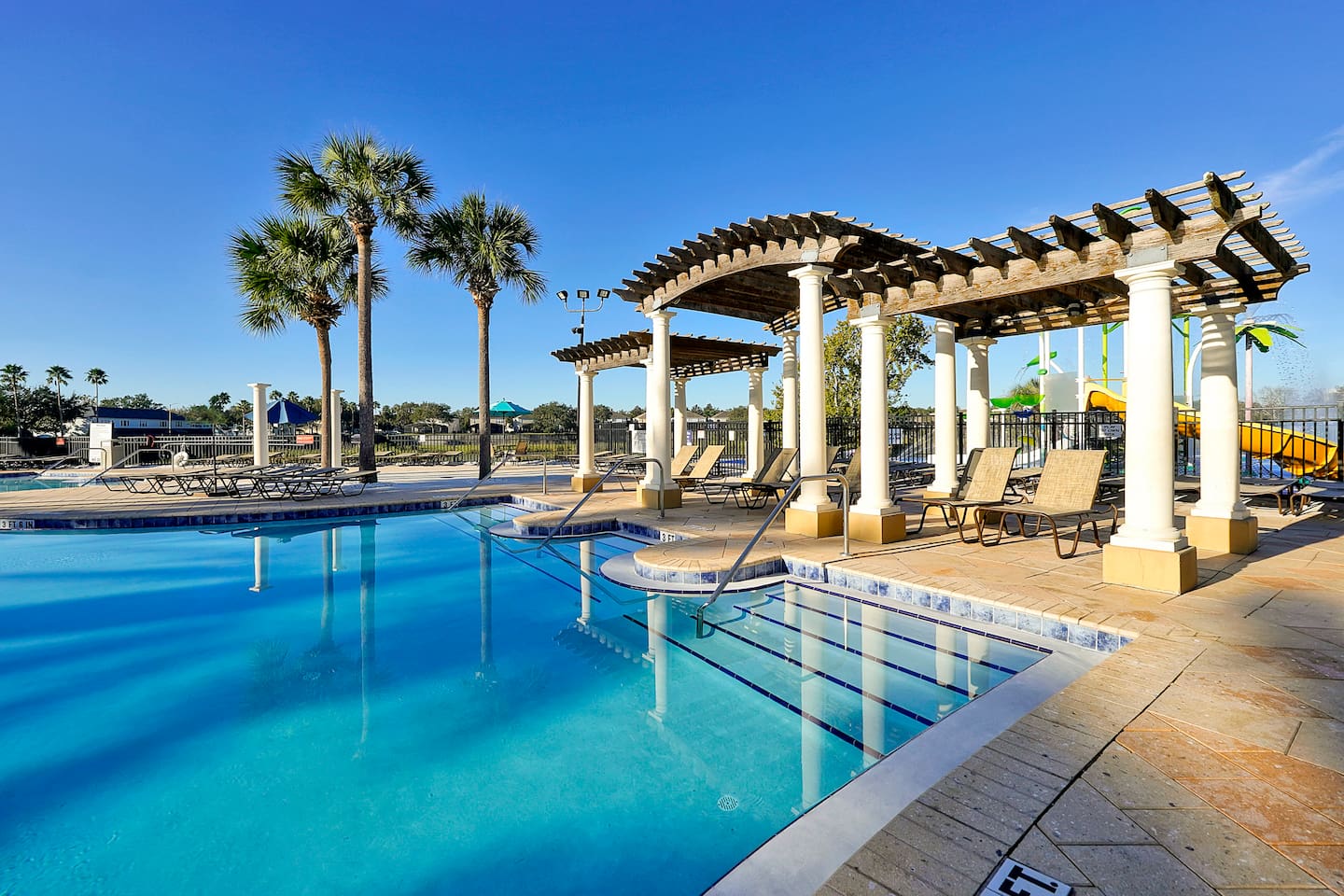 Resort pool with pergola shaded lounge seating.


