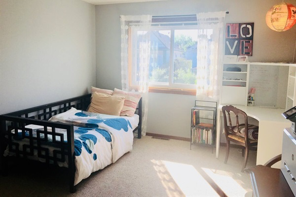 Cozy twin bed in a spacious bedroom with desk and work space.