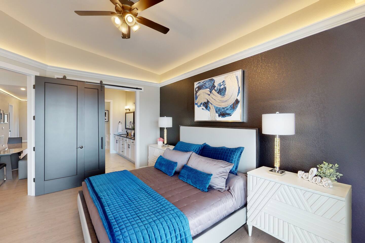 Master bedroom with modern decor, King size bed, private ensuite bathroom, large flat screen tv, surround sound system, ceiling fan, soffit lighting, sliding glass door, and access to the outdoor patio deck.