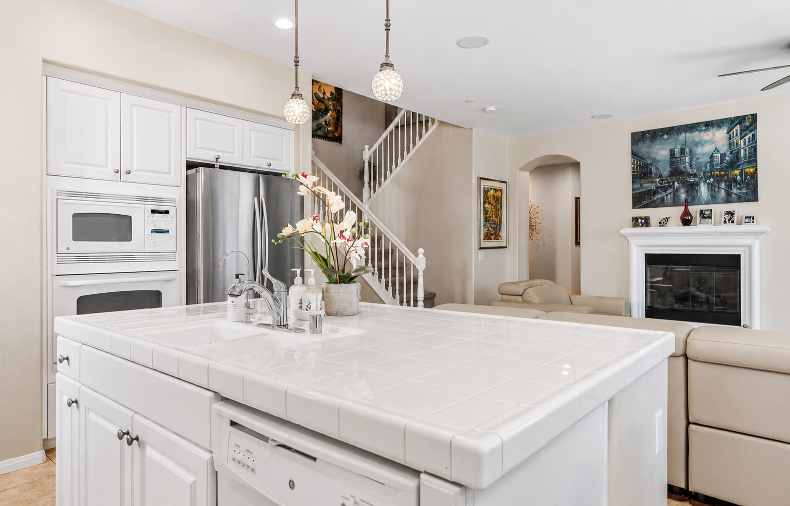 Kitchen island with lots of counter space, double ovens, and an open view to living room and stairs leading to the second level of the home 