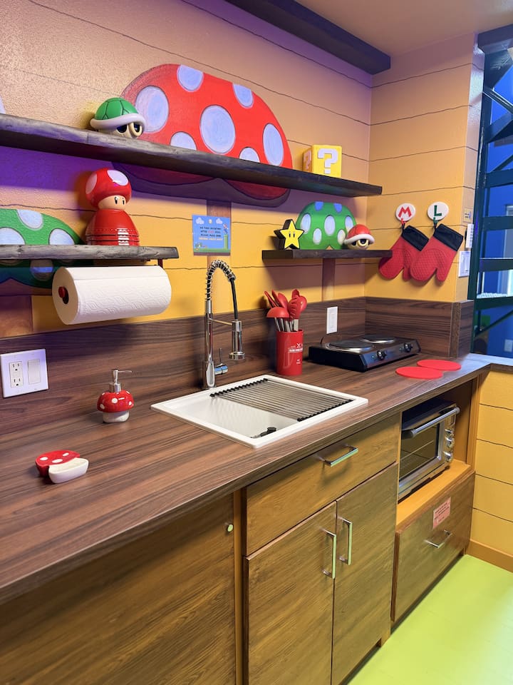 Playful Mario kitchen counter at Mario's Mini Mansion, Clermont, FL! Sink with flexible faucet, mushroom shelves, Toad figurine, and colorful Super Mario details make cooking and cleanup an exciting adventure for kids and adults.