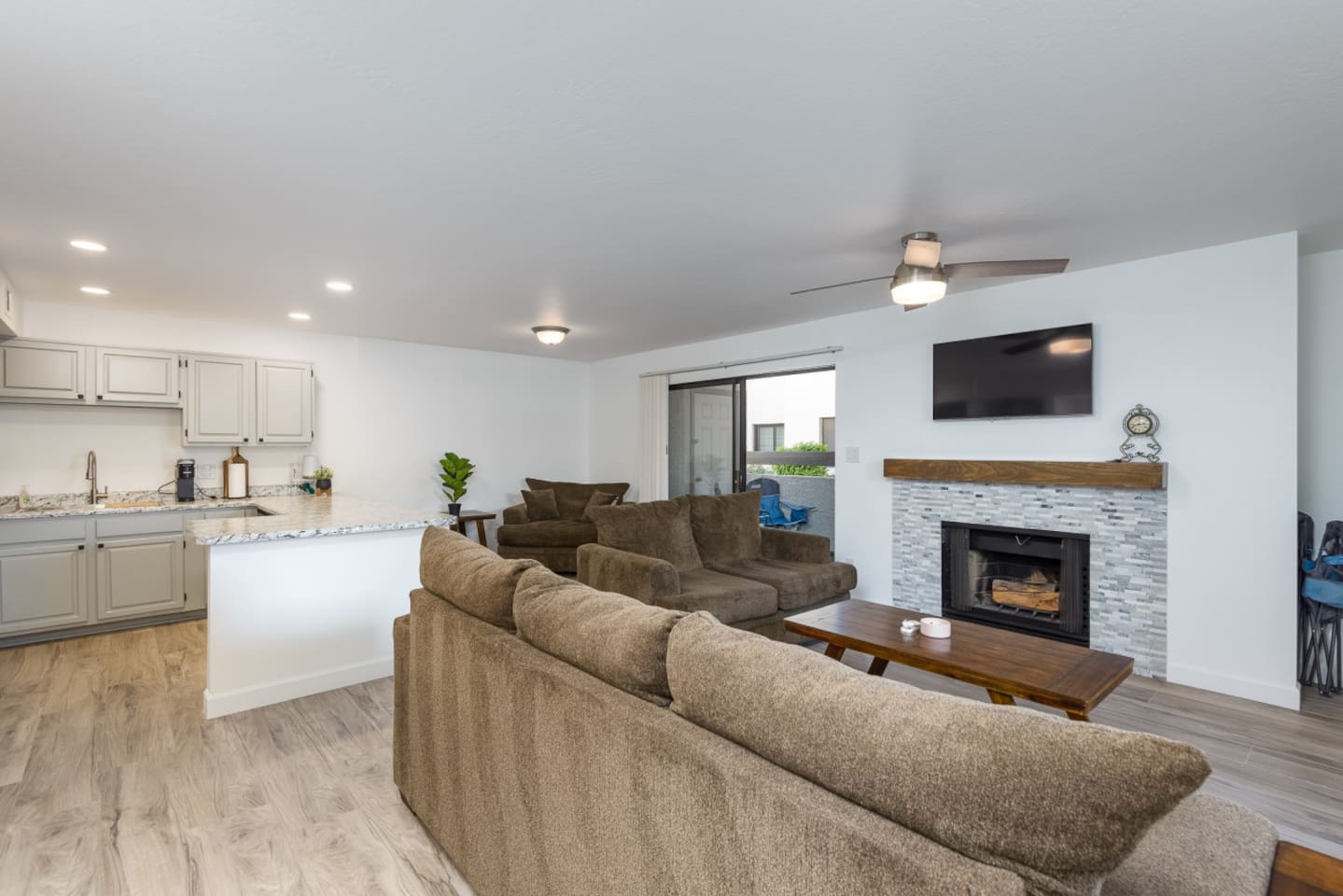Living room with soft seating, a fireplace, TV, and the kitchen just steps away.
