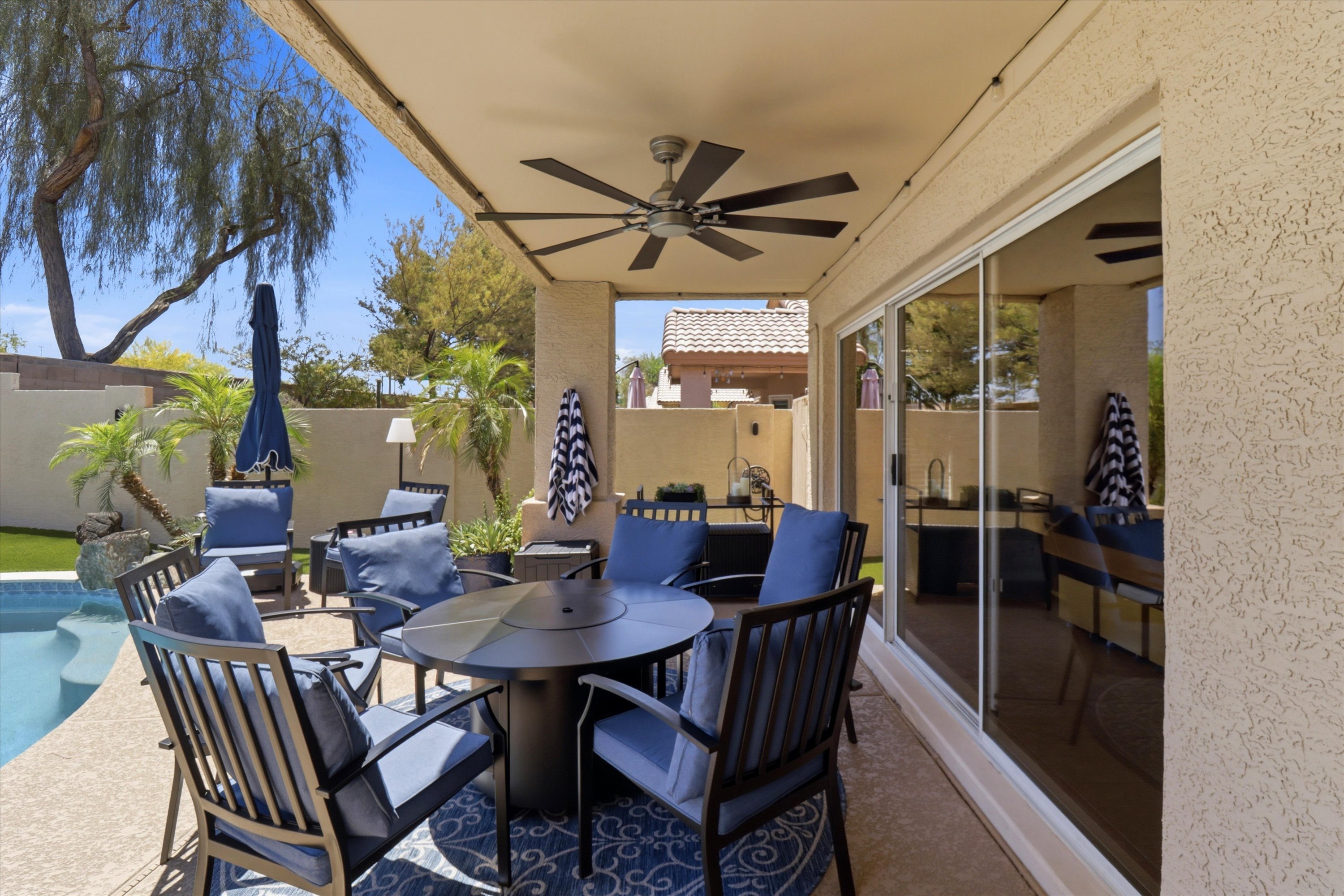 Covered patio dining area with pool views, ceiling fan, and shaded seating for outdoor meals or relaxed downtime.