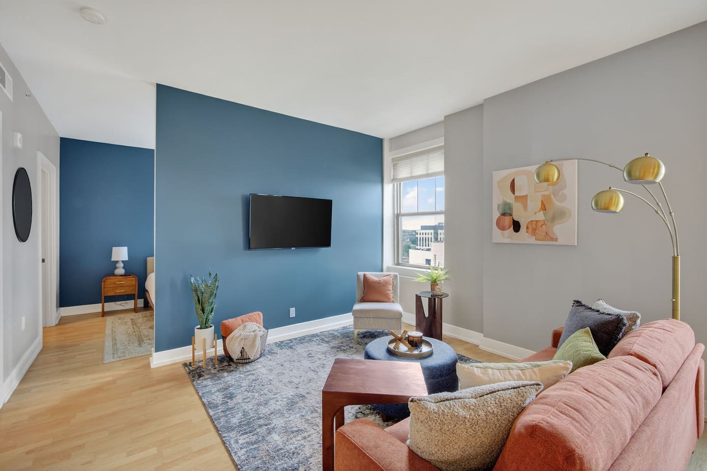Bright and inviting, the living room features a bold accent wall, large windows with city views, and chic furnishings. Curl up with a book, watch a movie, or enjoy the vibrant atmosphere of this modern escape.