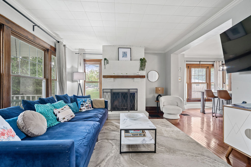 An oversized sofa complements the beautiful windows that fill the living room with natural light, highlighting the stunning features of this fully remodeled 100-year-old home.