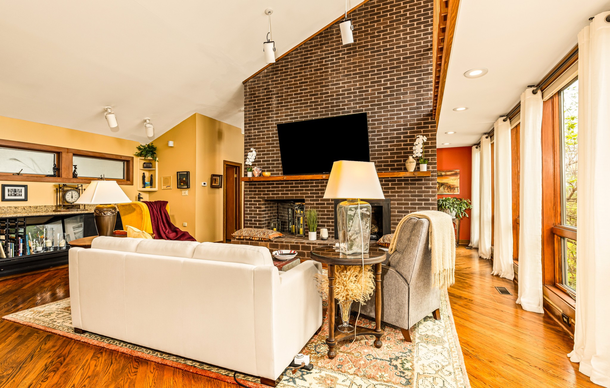 Soaring windows frame gorgeous sunrises and storms rolling by! Comfy seating, people you like - all together in the perfect place to hang out together in front of the fireplace! 75" Roku TV for watching shows or background music.