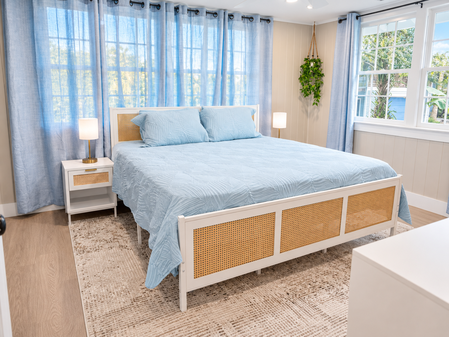 Cozy bedroom with blue quilted bedding, rattan frame, warm lamps, and calming décor.