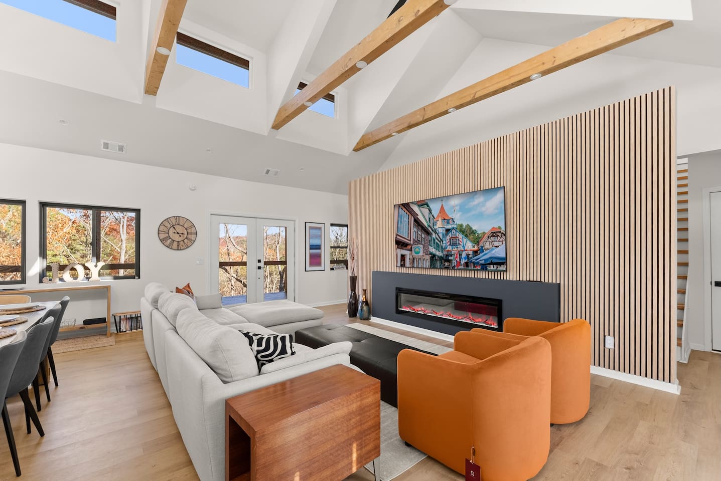 Spacious, modern living room with soaring ceilings, an electric fireplace, and a large TV
