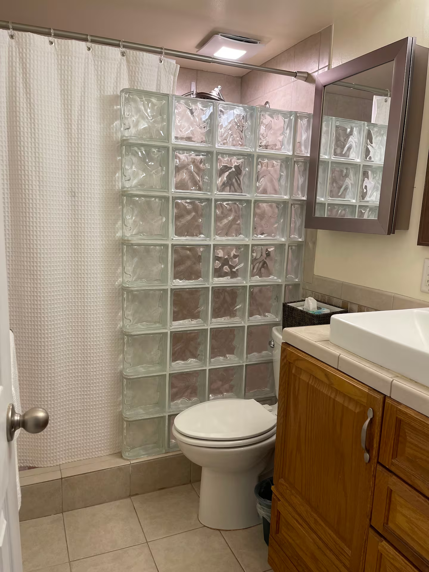 Clean, updated bathroom with walk-in shower and glass block feature wall for natural light.
