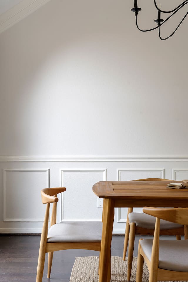 Enjoy a cozy dining area adorned with a wall mirror, inviting in the outdoor scenery through a window.