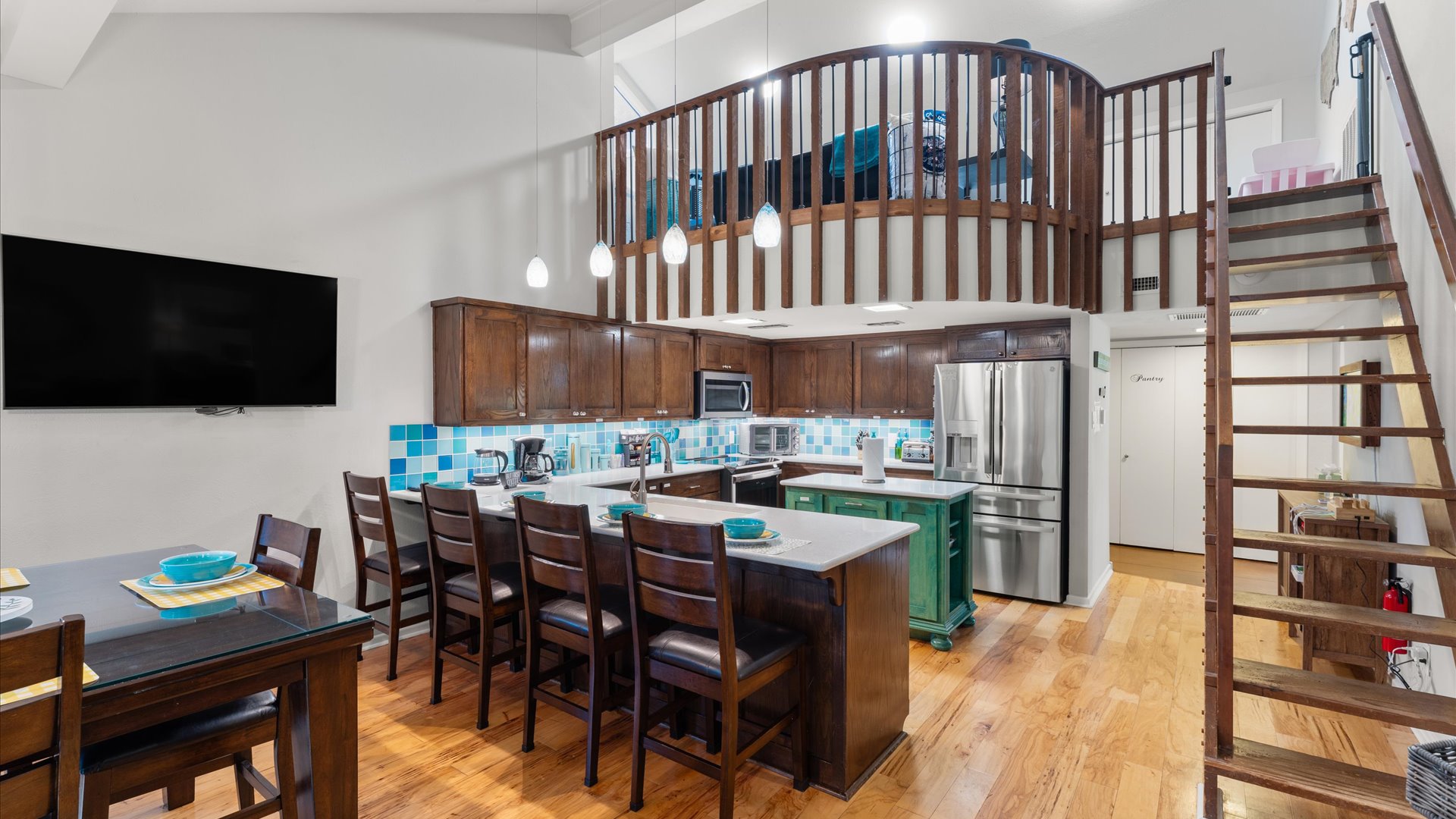 Stairs leading to the children’s play loft, a favorite spot for kids. A widened view of the kitchen is also visible. Note the stairs are steep, but there’s a baby gate at the top for safety.