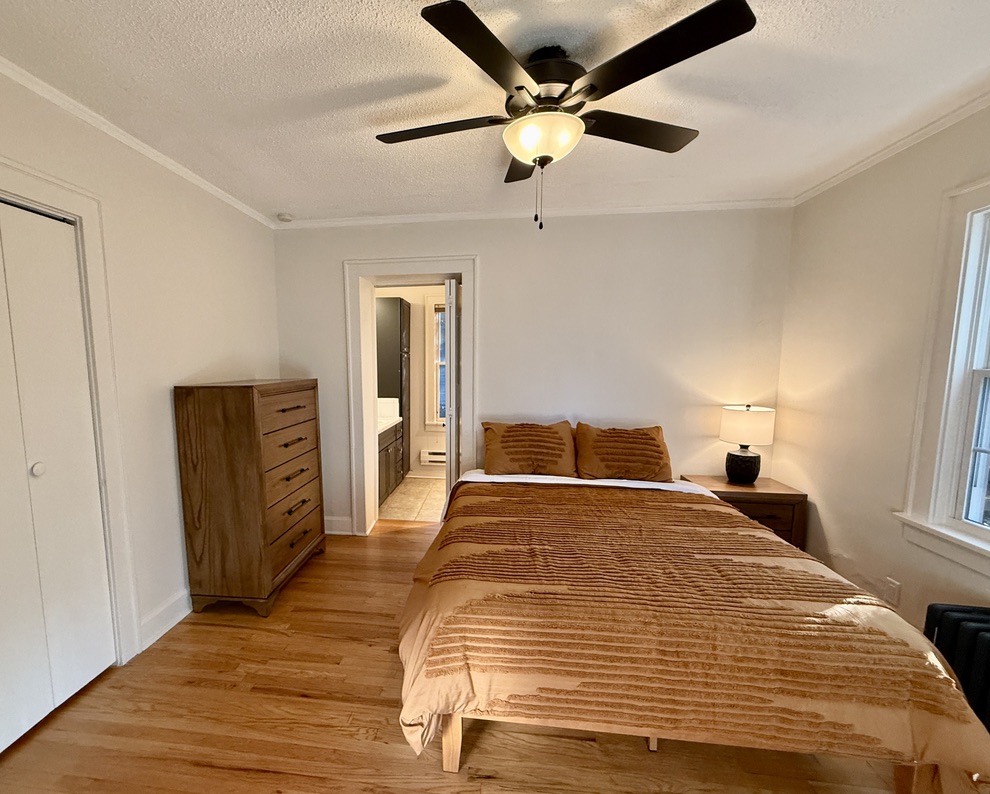 The second bedroom offers an Ensuite Bathroom, a plush Queen bed, large dresser, a closet with hangers, and side tables with charging lamps.