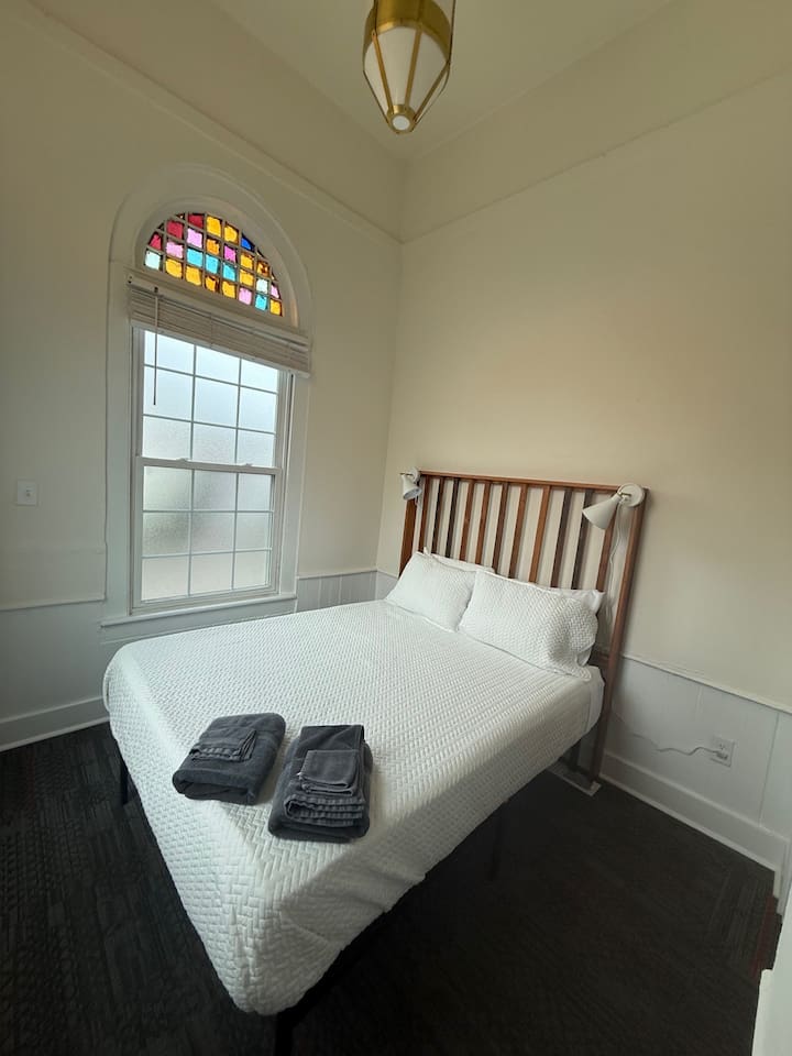 Cozy front bedroom featuring a queen bed, plush bedding, warm ambient lighting, and all the essential comforts for a restful stay.