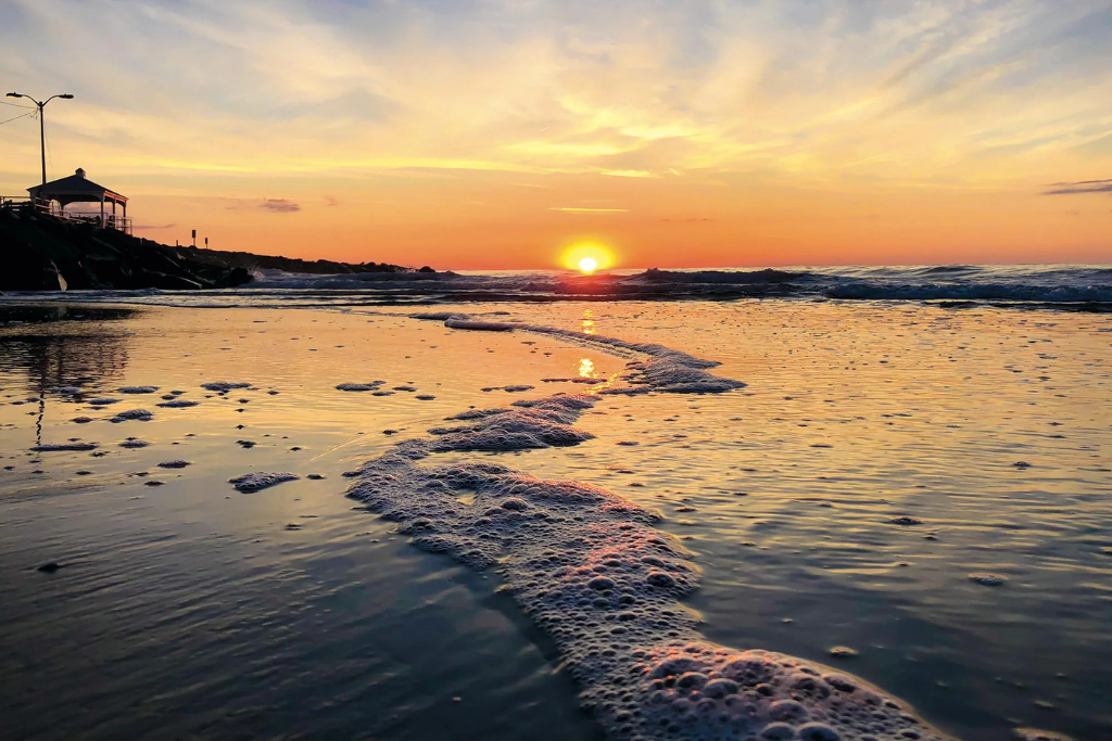 Golden sunset along the shoreline with gentle waves and open beach views. A peaceful coastal moment ideal for evening walks, quiet reflection, and enjoying the changing colors over the ocean.