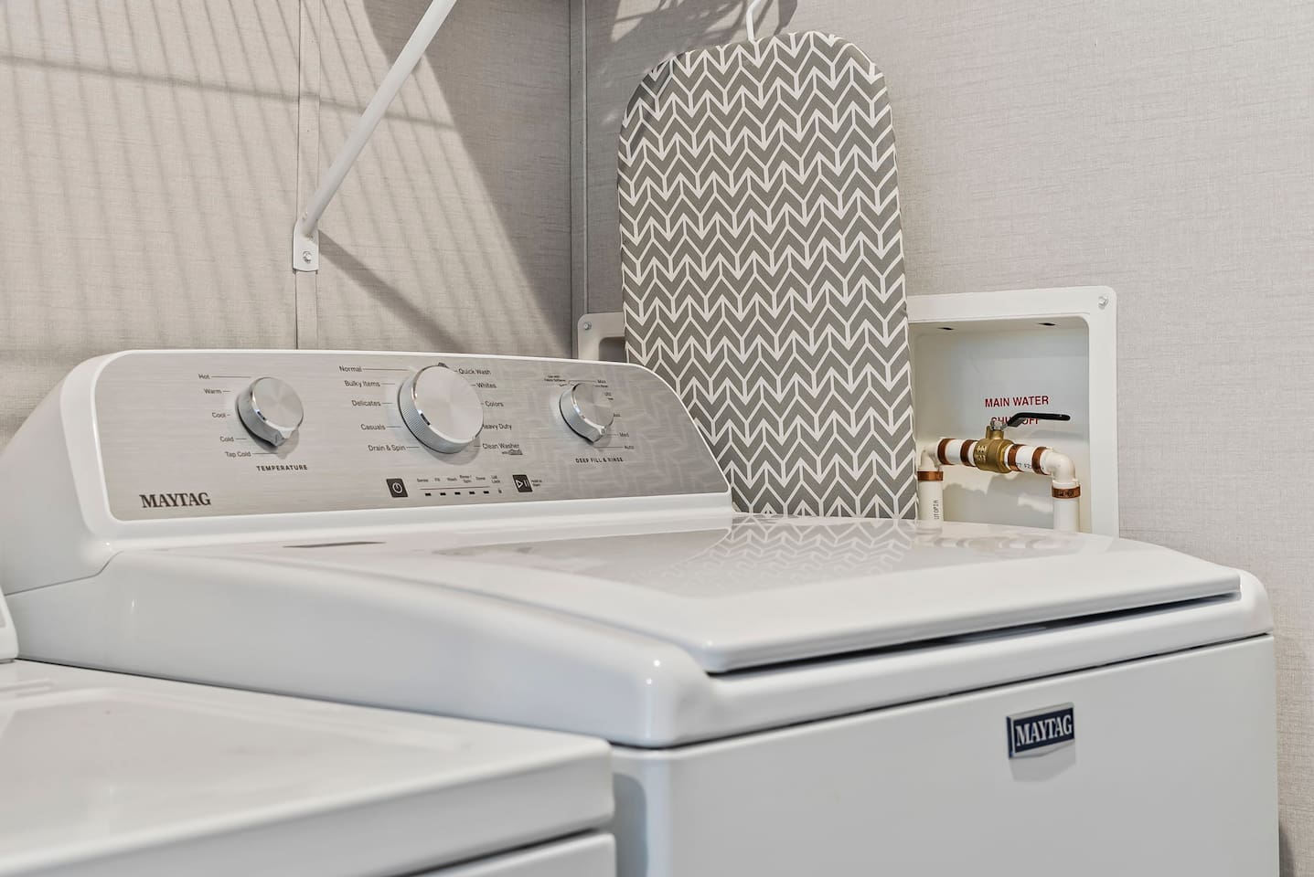 Modern washer setup with simple controls and nearby ironing essentials for added convenience.