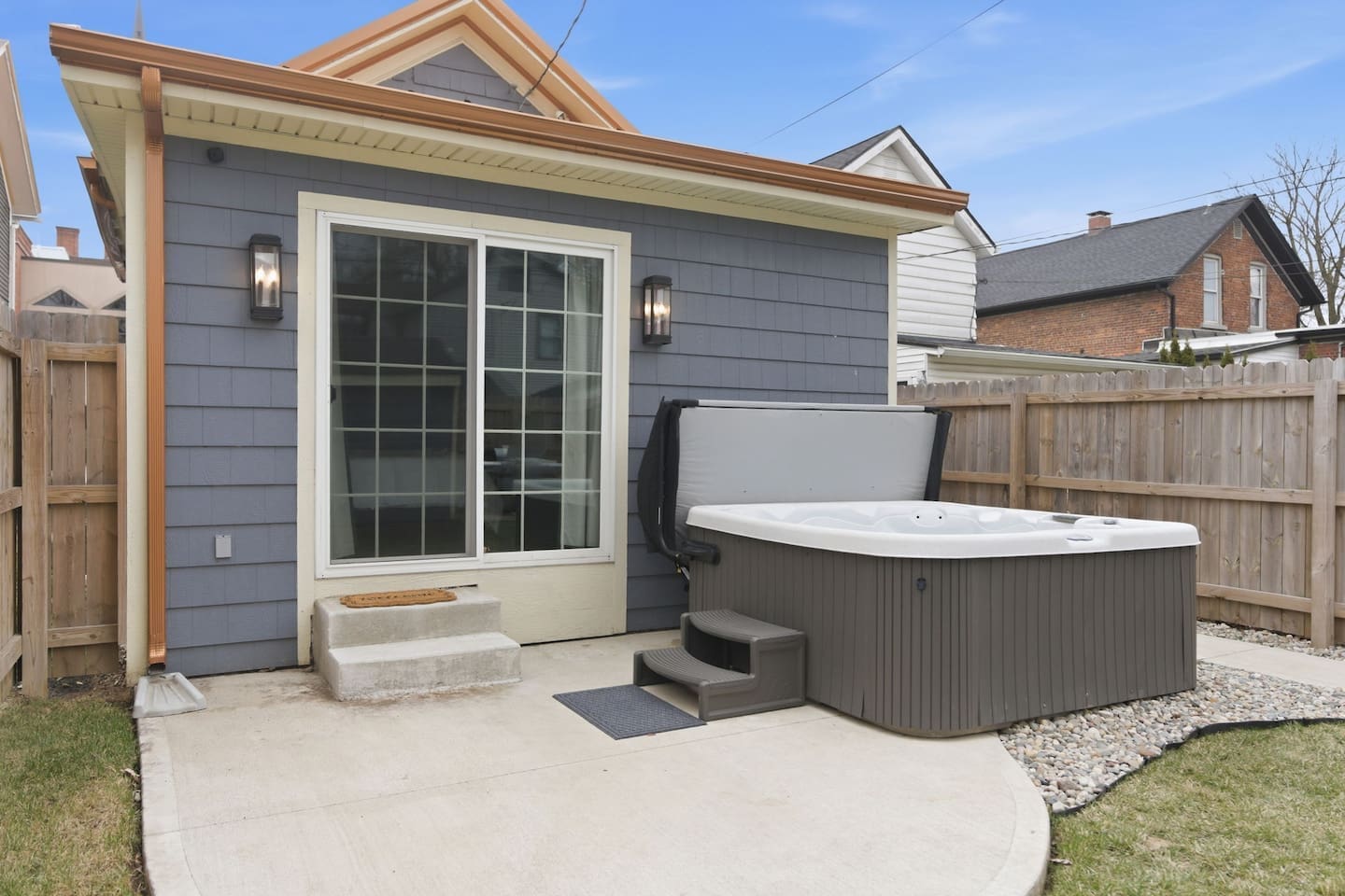 Backyard oasis featuring a spacious hot tub and easy access from the home