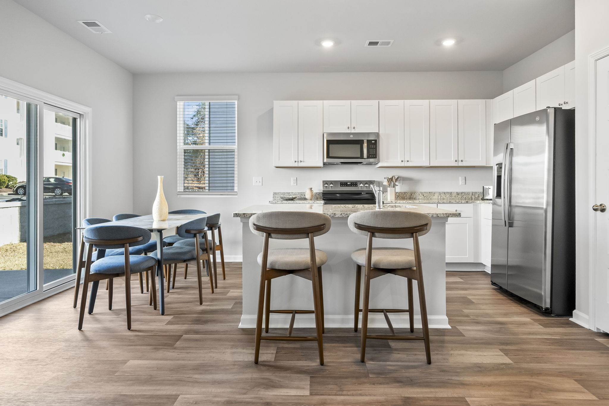 Modern kitchen with granite countertops and stainless steel appliances, dining room table seats 6