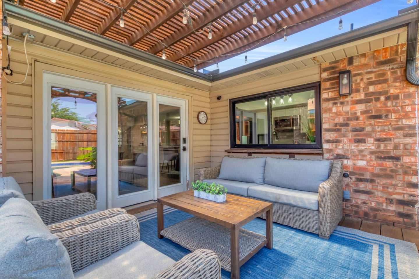 Zoomed in view of the covered patio's sitting area, coffee table, and poolside vibes. 