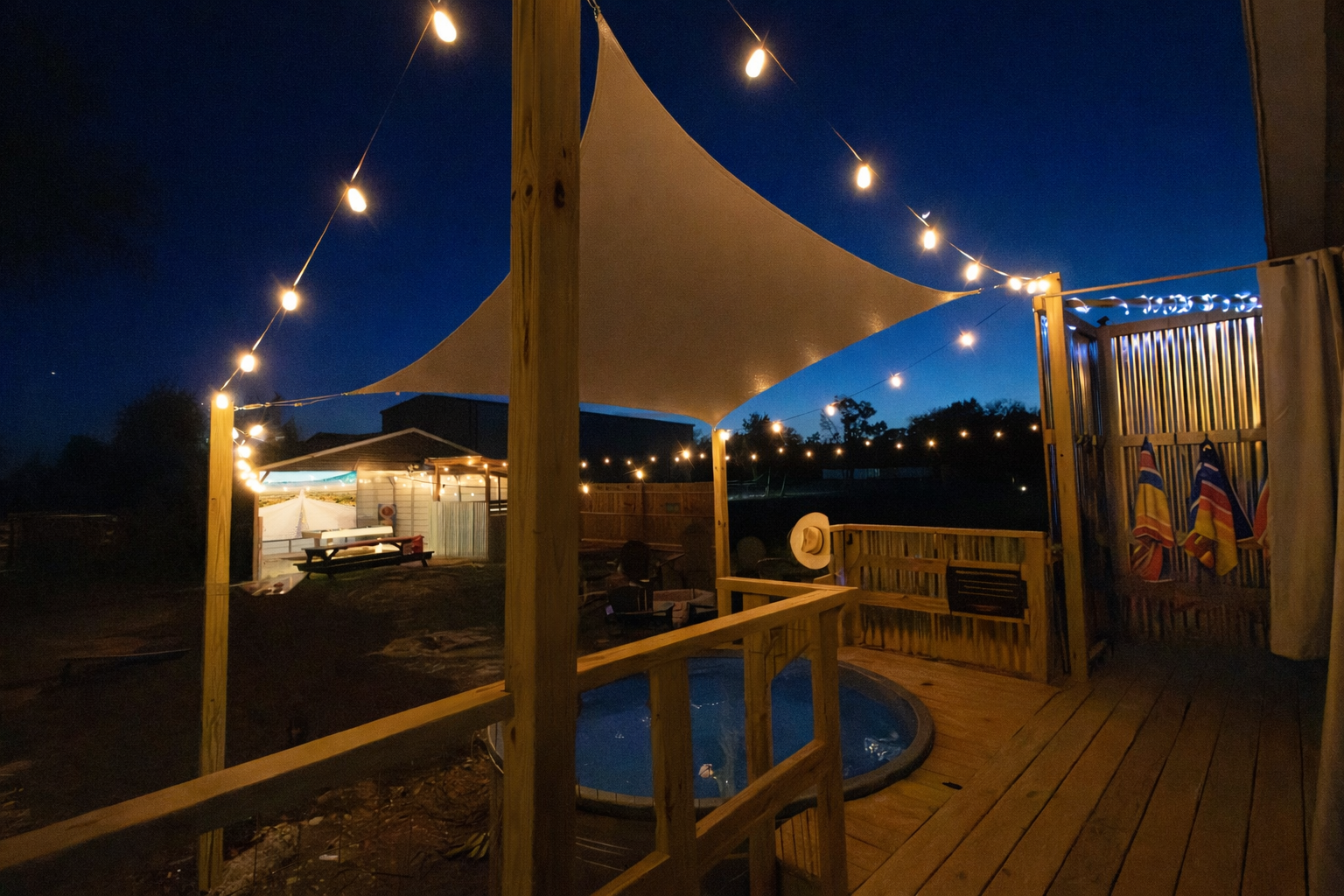 Private Game Barn Retreat lit by string lights, cowboy pool, and 17ft outdoor movie screen — designed for unforgettable evenings.