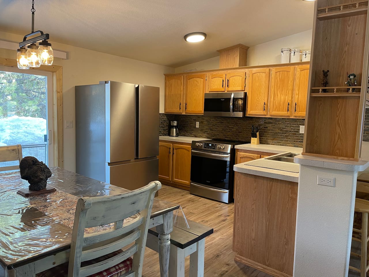 Kitchen with Updated Appliances, Backsplash, Faucet, Cupboard Door Handles, Light, Table, and Flooring