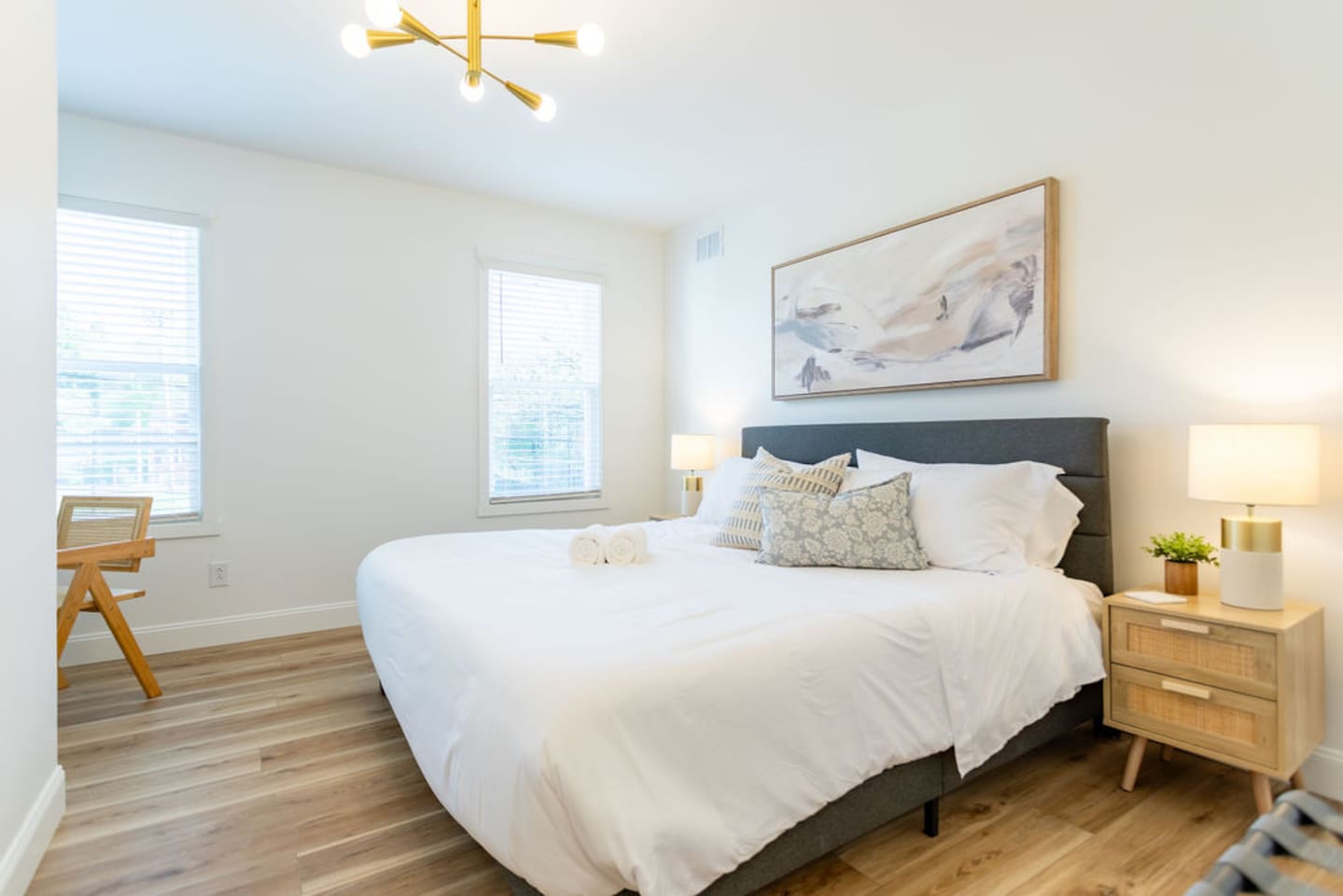 View of the king-size bed with a beautiful painting in the background, complemented by side tables and lamps for a cozy, stylish touch.