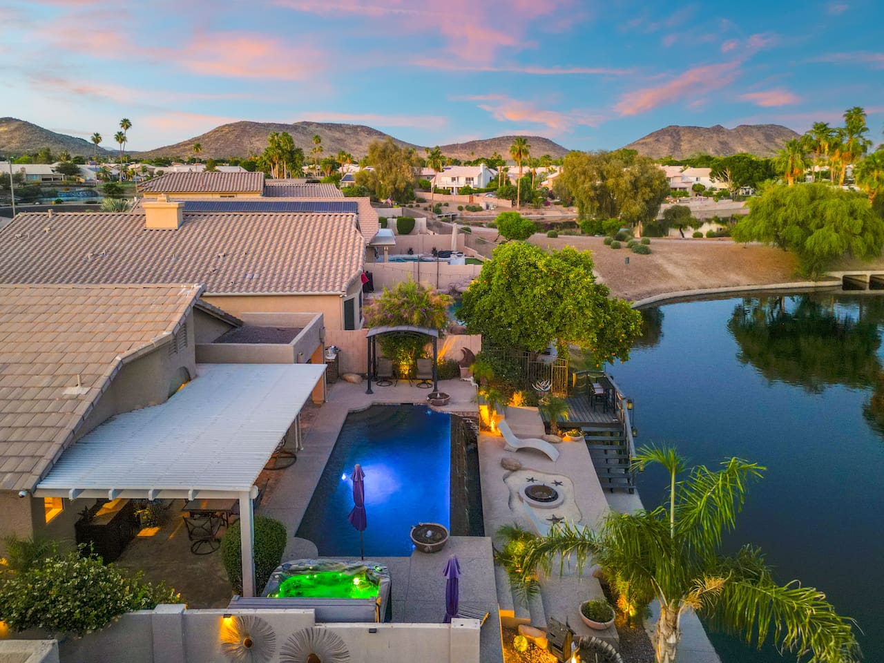 The pool glows after dark while the hot tub steams and the lake shimmers just beyond the yard — this is what Arizona evenings were made for.
