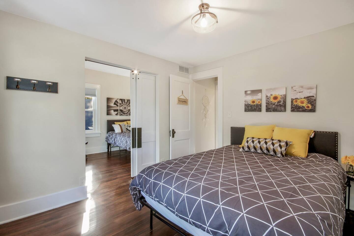 This main floor bedroom features a queen sized bed, sunflower decor, and part of a pair of rooms separated by a barn door.