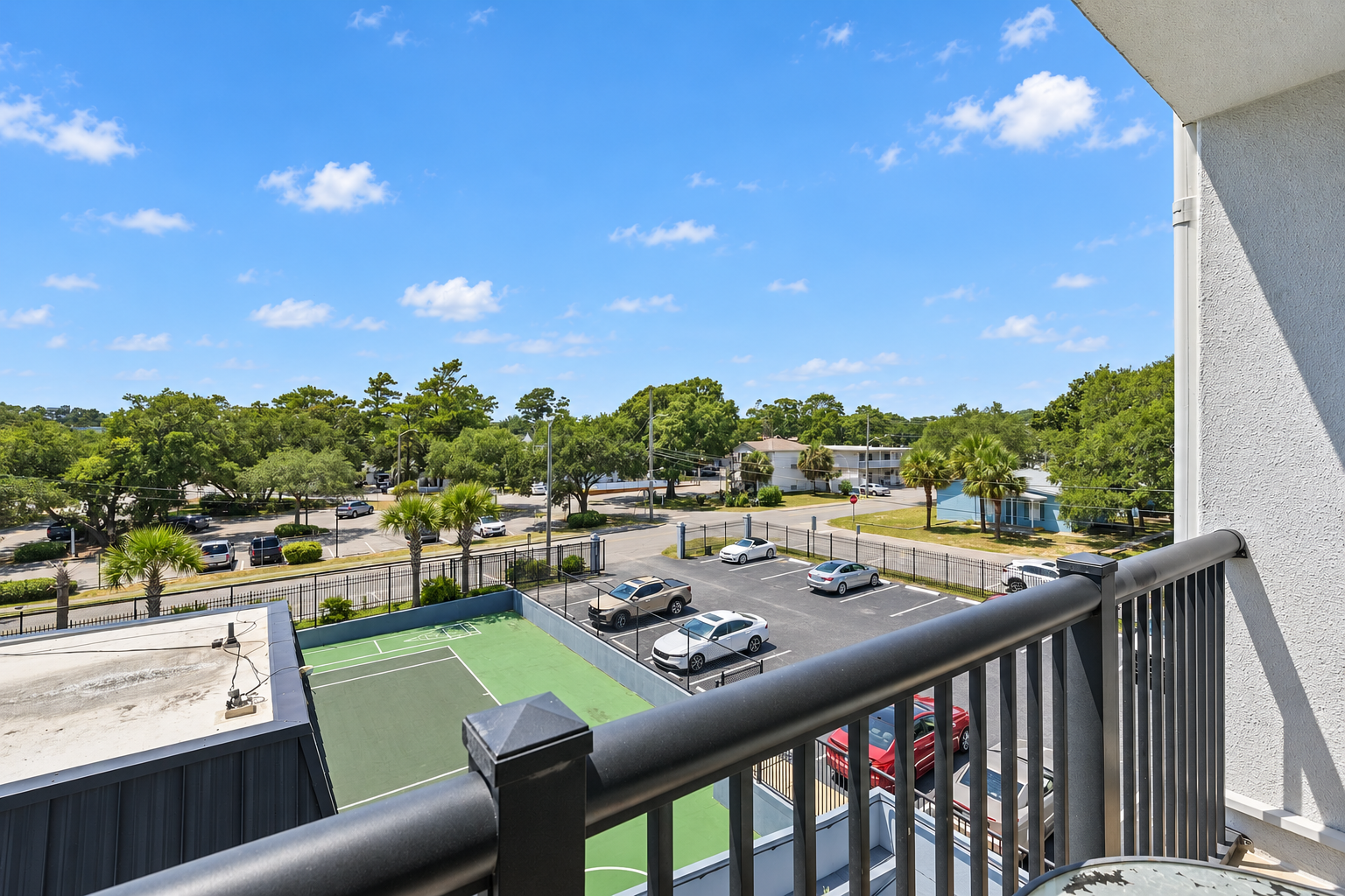 Covered balcony with table seating, chairs, and a treetop view over the Holiday Towers area.